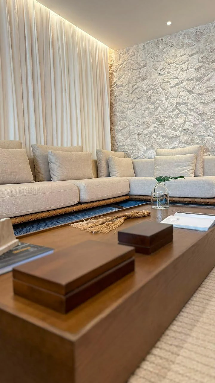 Sala de estar do decorado com sofá em linho claro, parede de pedra e mesa de centro em madeira