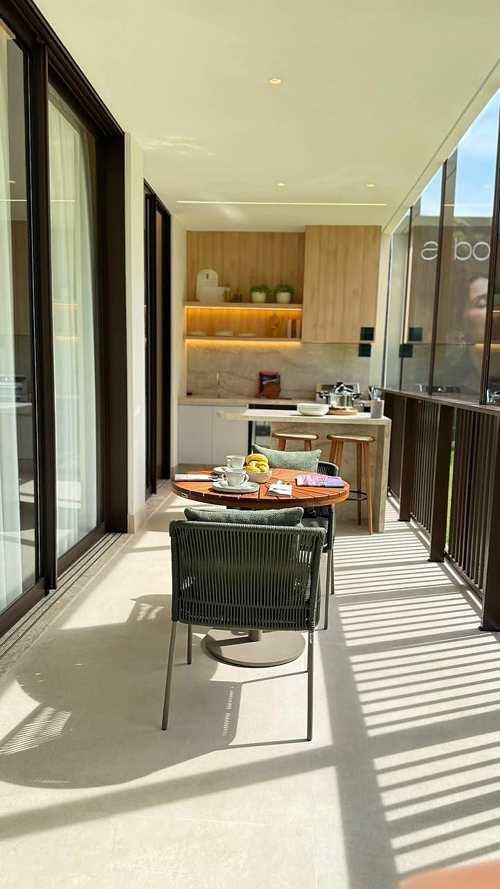Varanda gourmet do decorado com mesa redonda de madeira, cadeiras verdes e cozinha de apoio