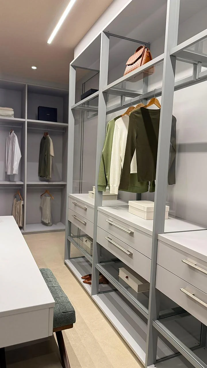 Closet com estrutura metálica aberta, gaveteiros e cabideiros